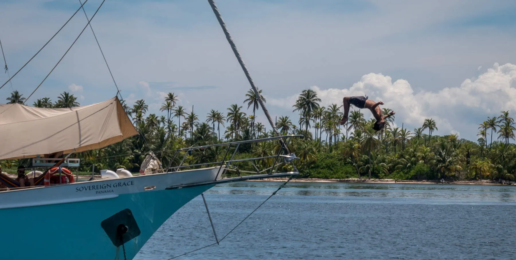 Sovereign Grace at anchor with a guest diving off the bow in San Blas