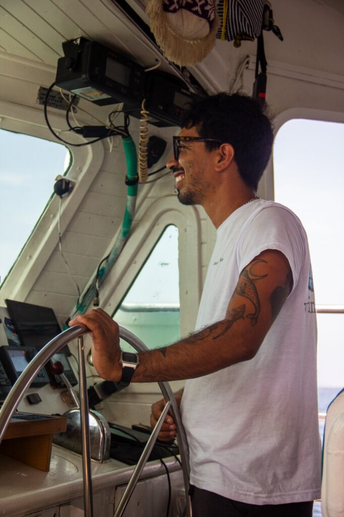 Captain Daniel smiling at the helm of the Wild Card sailboat