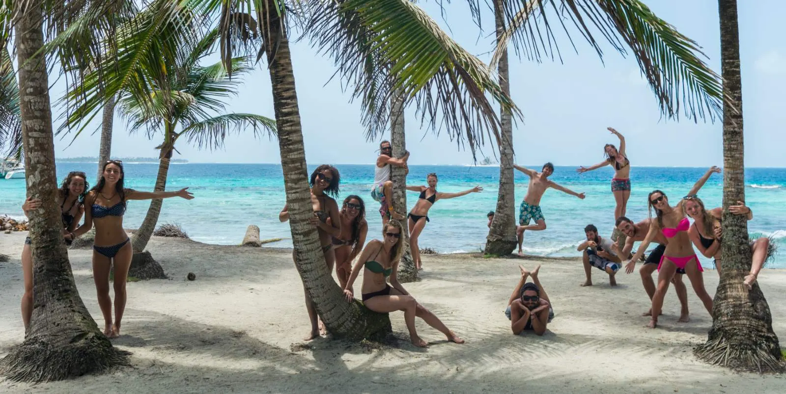 Group of backpackers posing between palm trees on a San Blas beach