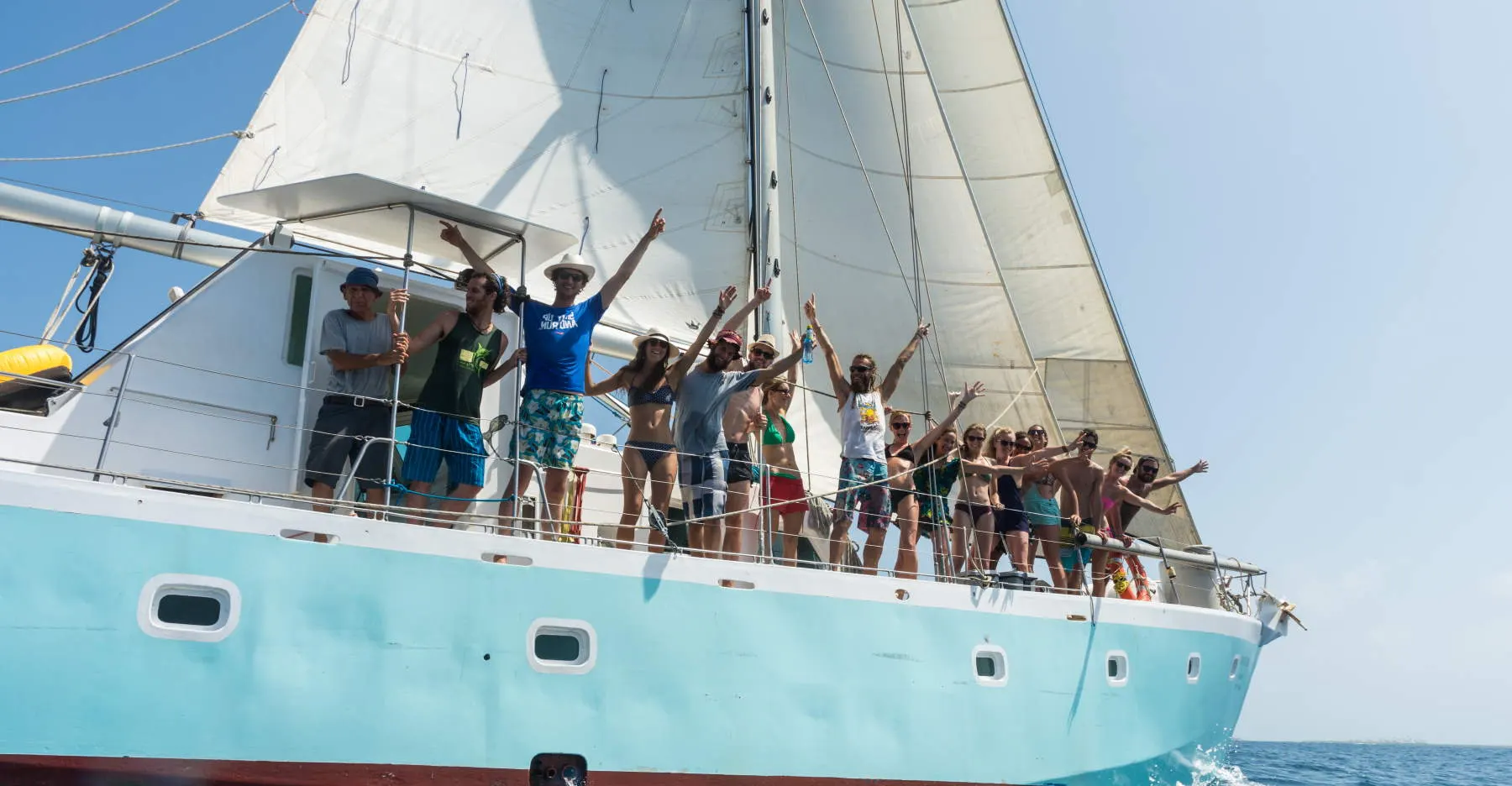 Passengers cheering on the deck of the Wild Card sailboat